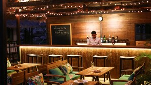 A cozy bar area with wooden furniture, string lights, and a chalkboard sign.