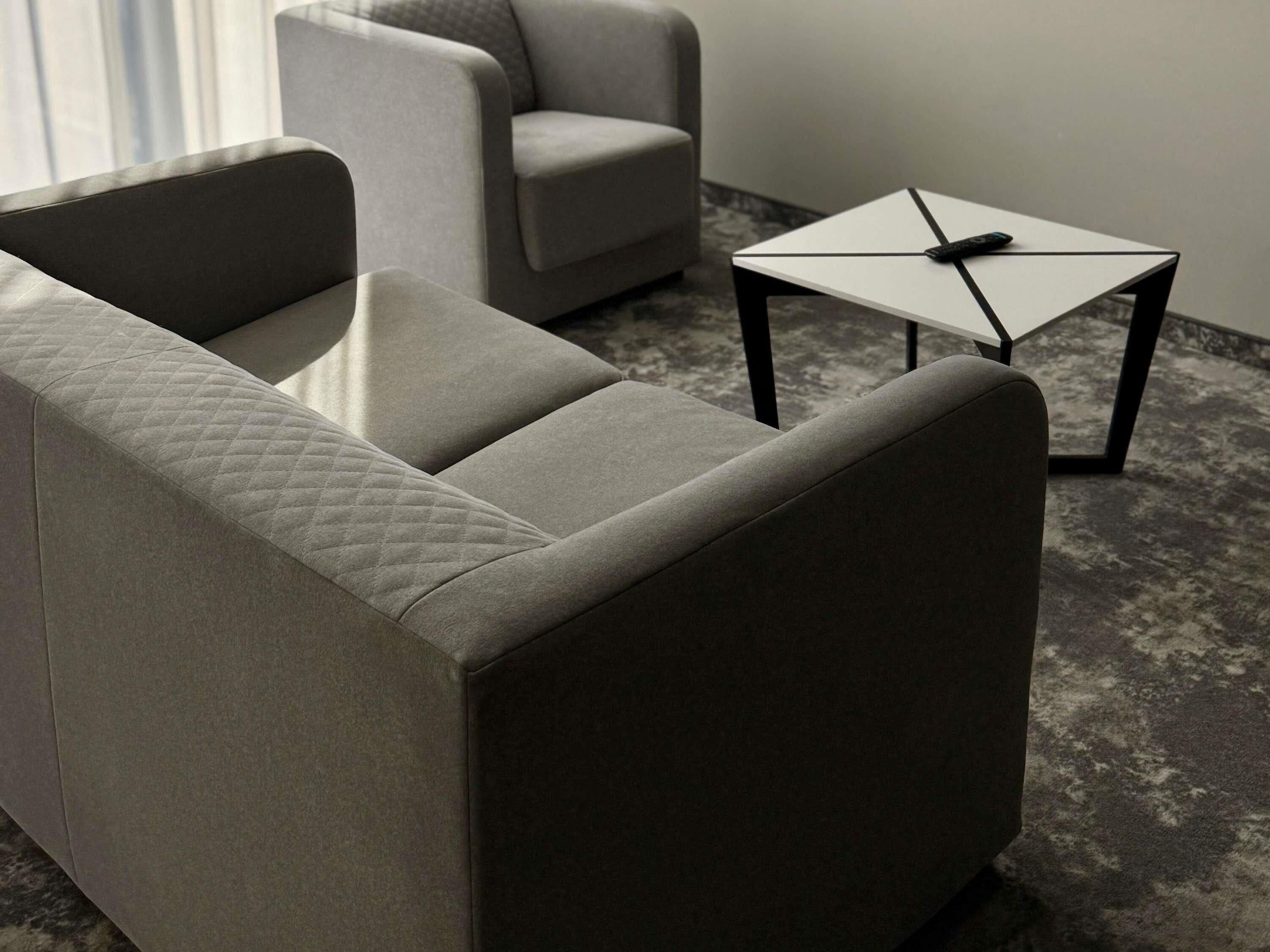 A modern living room with a grey sofa, a small white table, and a remote control on the table.