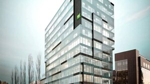 A modern high-rise building with a glass facade and a green flag on the corner. - ibis Styles Warszawa City (Warsaw)