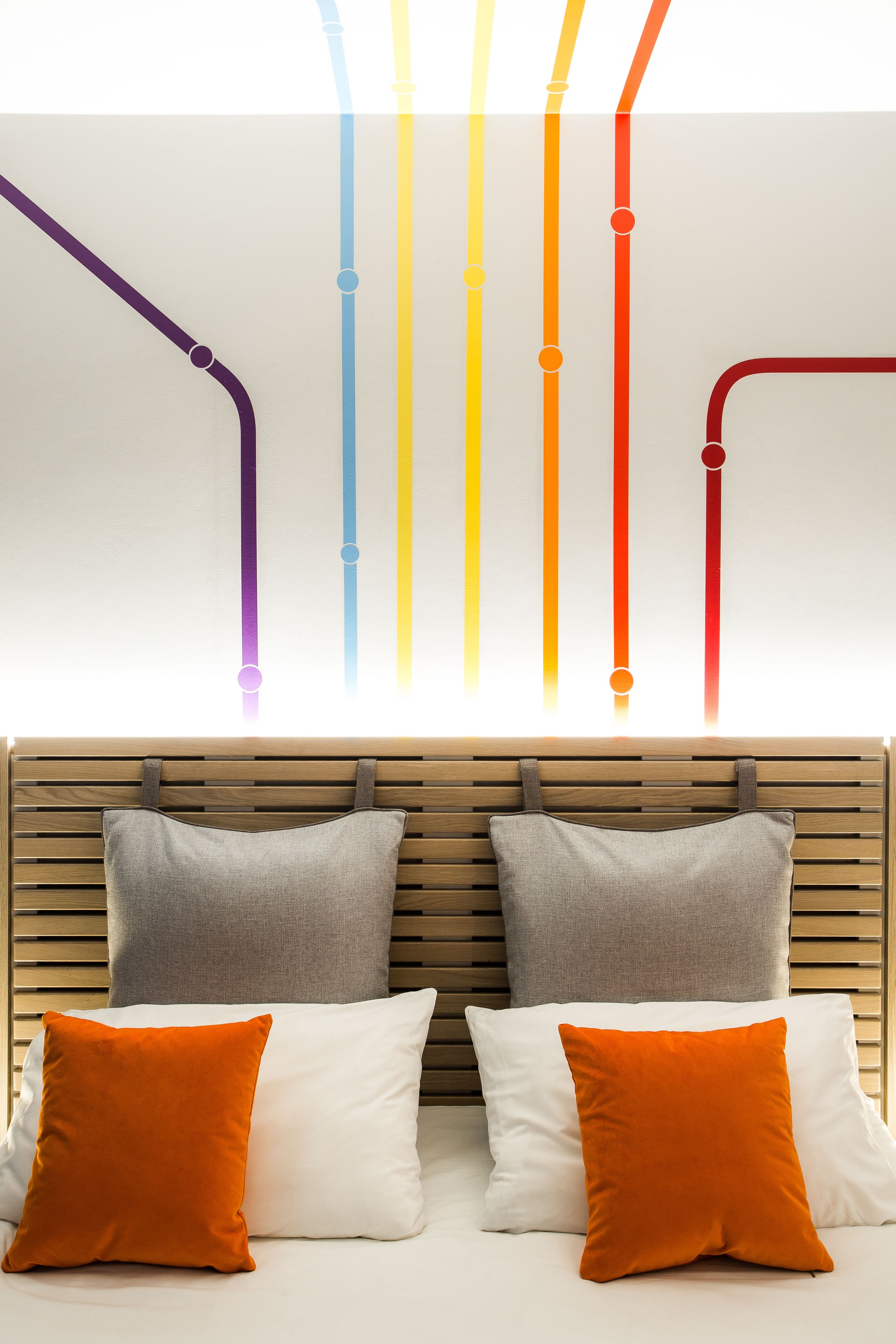 A bed with two pillows, one white and one orange, and a wooden headboard.