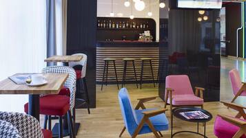 A modern cafe with wooden tables and chairs, a bar area with stools, and hanging pendant lights.