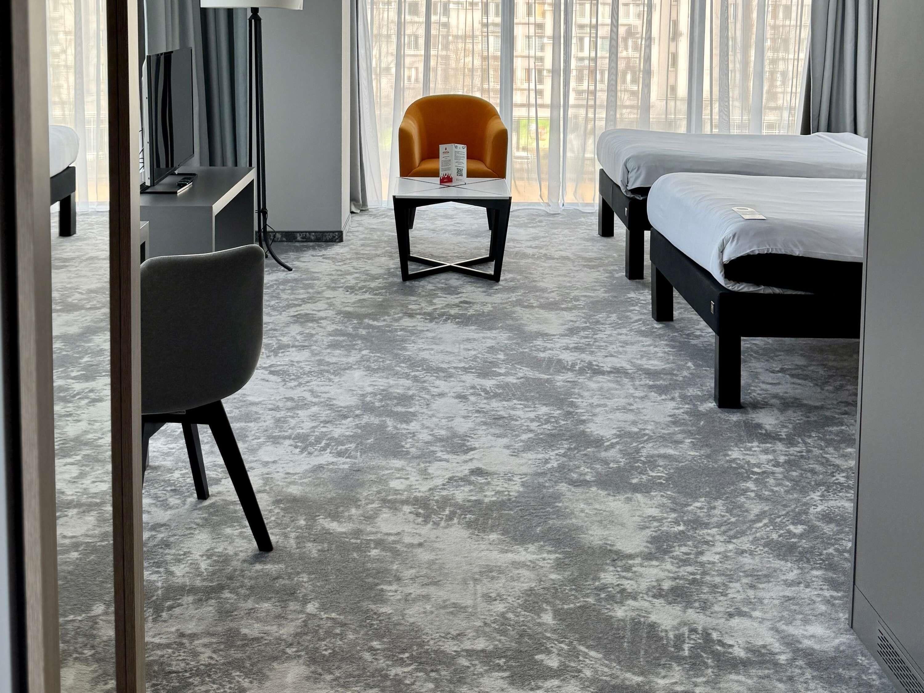 Una habitación de hotel con cama, escritorio, silla y una mesita.
