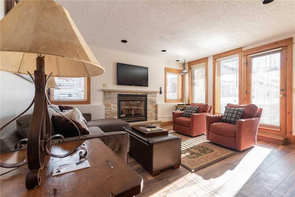 A living room with a fireplace, leather sofas, a coffee table, and a TV mounted on the wall.
