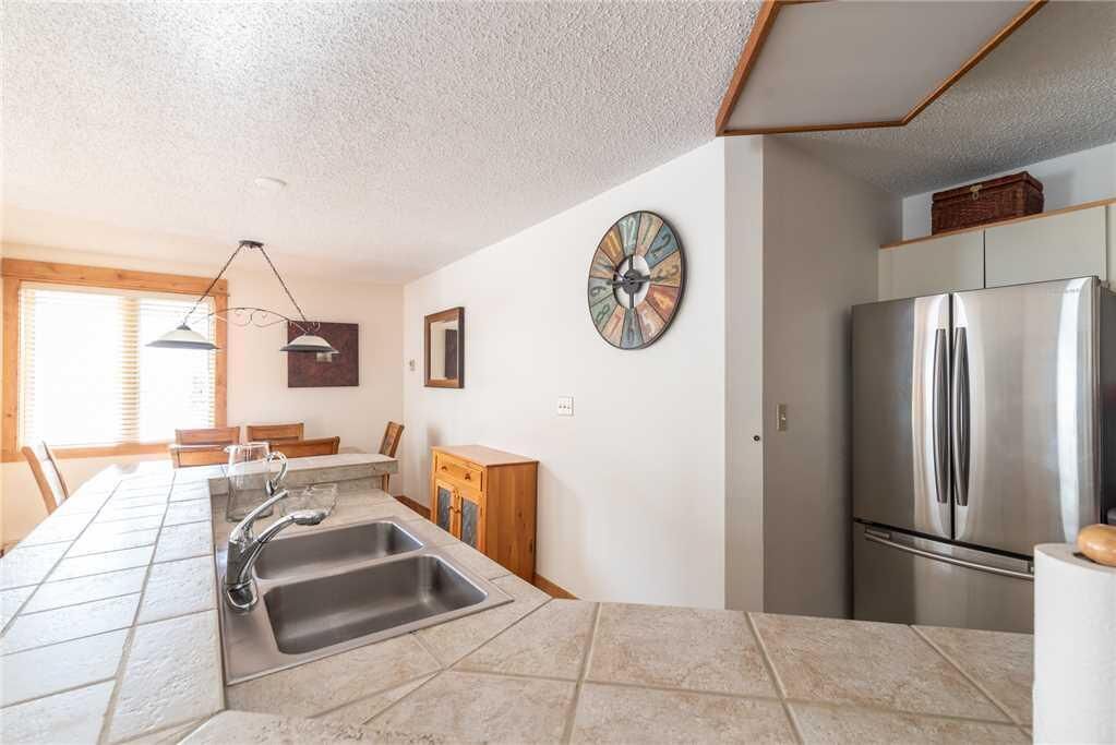 A modern kitchen with a stainless steel refrigerator, a sink with a faucet, and a dining area with a table and chairs.
