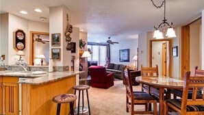 A spacious kitchen with a central island, wooden chairs, and a dining table. There are ceiling fans and pendant lights. - 1201 Trappeur's Lodge, Trappeur's Crossing Apartment 2 (Steamboat Springs)