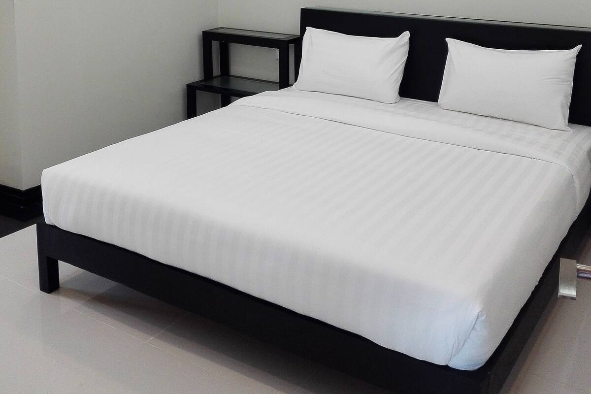 Een moderne hotelkamer met een groot bed, een nachtkastje en een airconditioning op de muur.