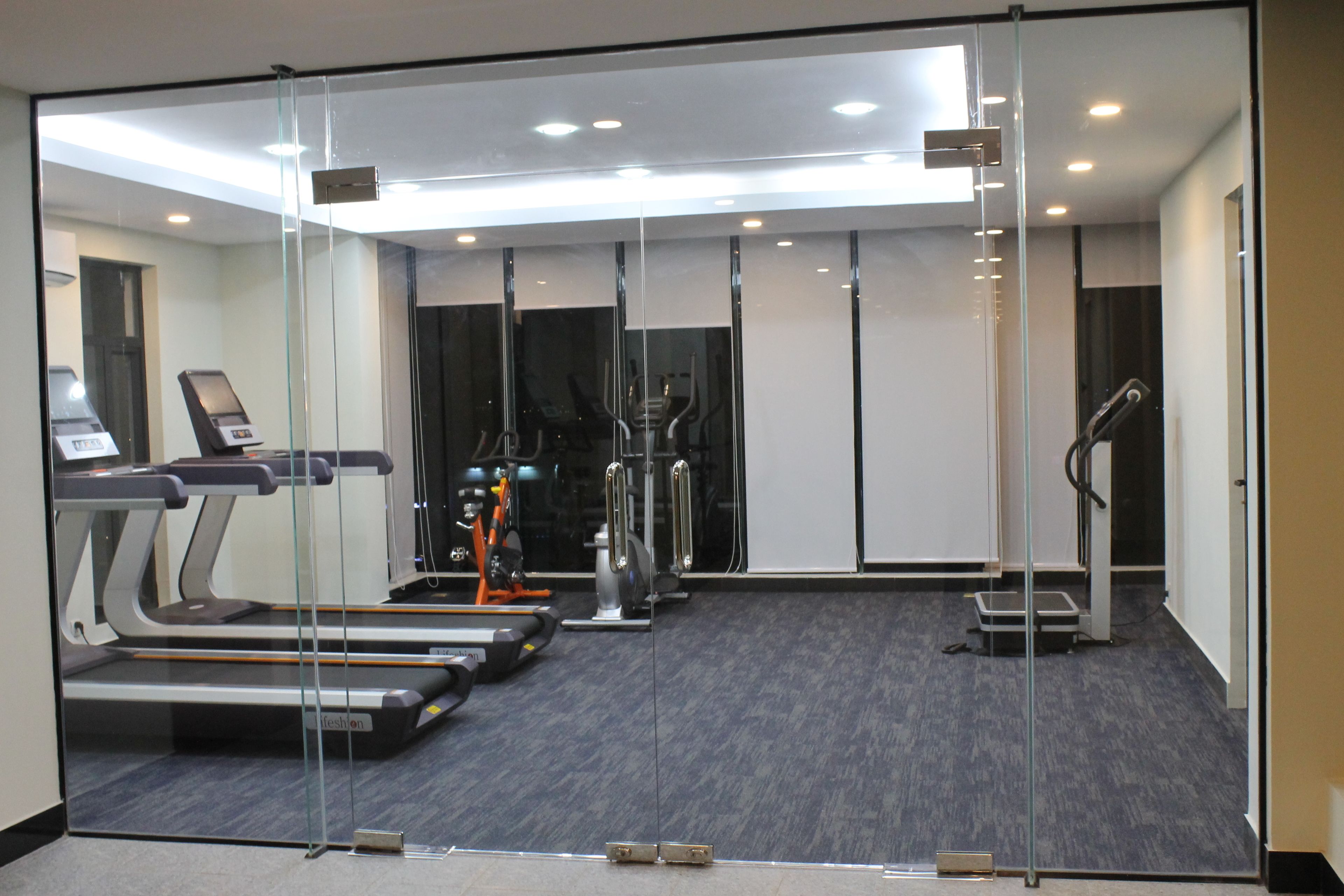 Un gimnasio moderno con cintas de correr, bicicletas estáticas y una máquina de remo.