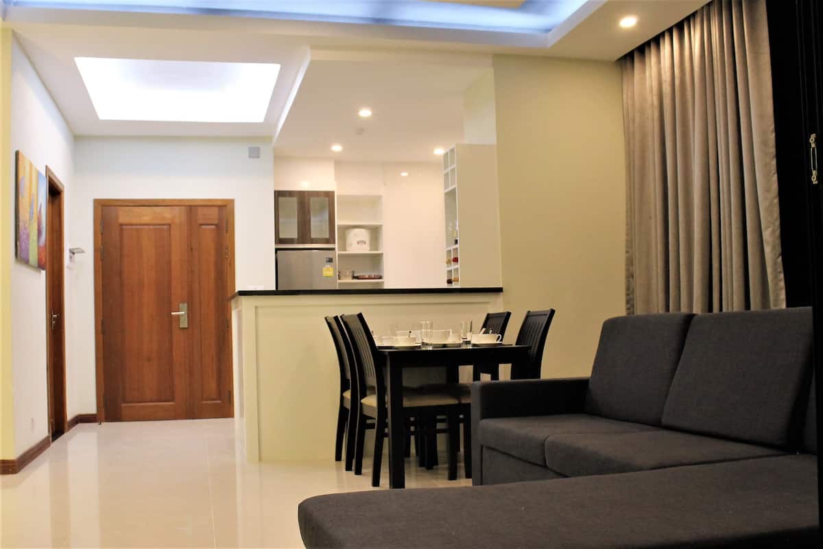 Een moderne woonkamer met een bank, eettafel, stoelen en een keuken in de achtergrond.