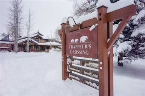 A wooden sign with the text "TRAPPEUR'S CROSSING" and directional arrows pointing to various lodges.
