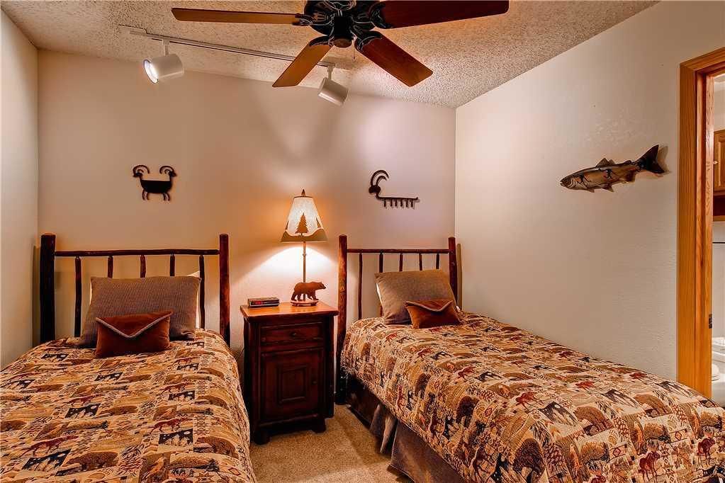 A bedroom with two beds, a nightstand, a ceiling fan, and wall decorations including animal figures.