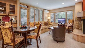 A cozy living room with a sofa, a dining table with chairs, a TV, and a fireplace. - 1210 Trappeur's Lodge, Trappeur's Crossing Apartment 1 (Steamboat Springs)