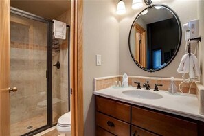 A bathroom with a glass-enclosed shower, a white toilet, a vanity with a sink, and a large mirror. - 1302 Trappeur's Lodge, Trappeur's Crossing Apartment 3 (Steamboat Springs)
