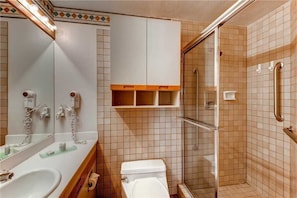 A bathroom with a toilet, sink, mirror, and shower area. - 1303 Trappeur's Lodge, Trappeur's Crossing Apartment 2 (Steamboat Springs)