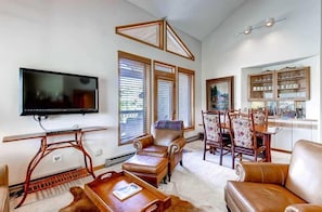 Relax in this stylish living room with a flat-screen TV, leather armchairs, and a dining area.