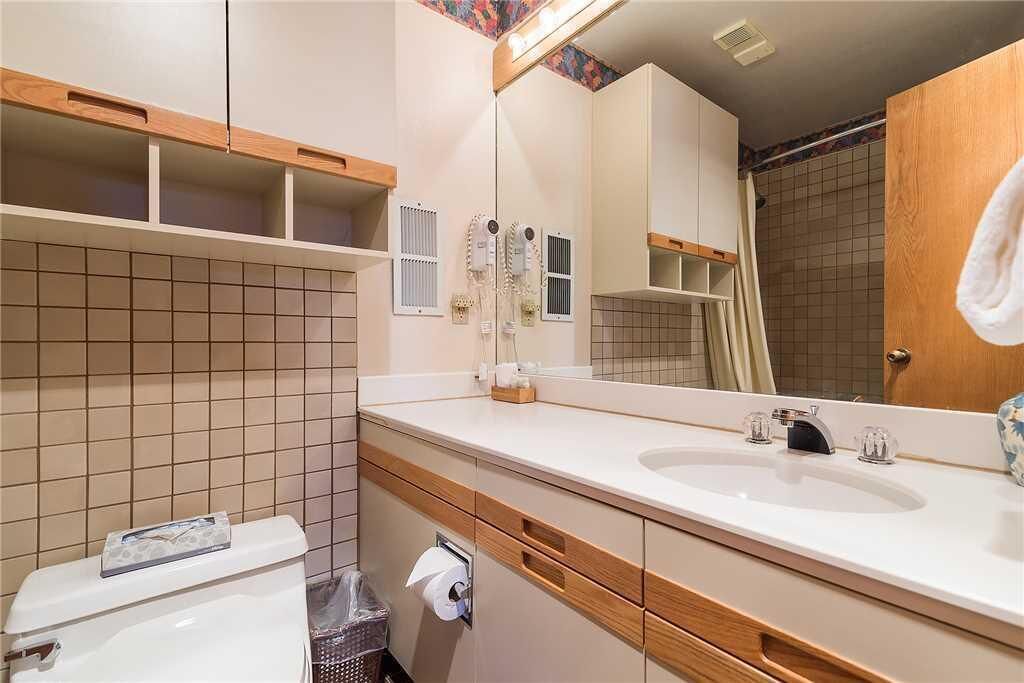 A bathroom with a white sink, wooden vanity, and a mirror.