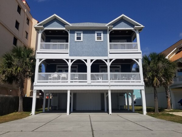 A two-story building with a balcony on the ground floor and a garage at the front. - Fabulous views  - right across the street from the beach! (Carolina Beach)