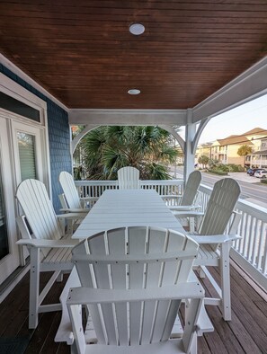 A covered porch with a wooden table and white Adirondack chairs. - Fabulous views  - right across the street from the beach! (Carolina Beach)
