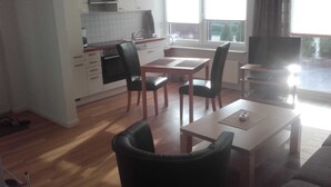 A compact living space with a kitchenette, dining area, and a TV. - Apartment Berger - Apartment (Timmendorfer Strand)