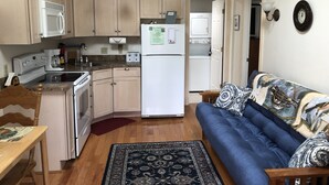 A compact kitchen with a refrigerator, microwave, and stove. There's a blue sofa and a patterned rug in the living area. - Super Clean, Fully-Equipped Private Suite 1 Mile from Acadia (Bar Harbor)