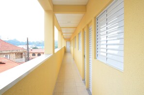 A corridor with yellow walls, white ceiling, and windows with blinds. - Studio Ana Laura (São Paulo)