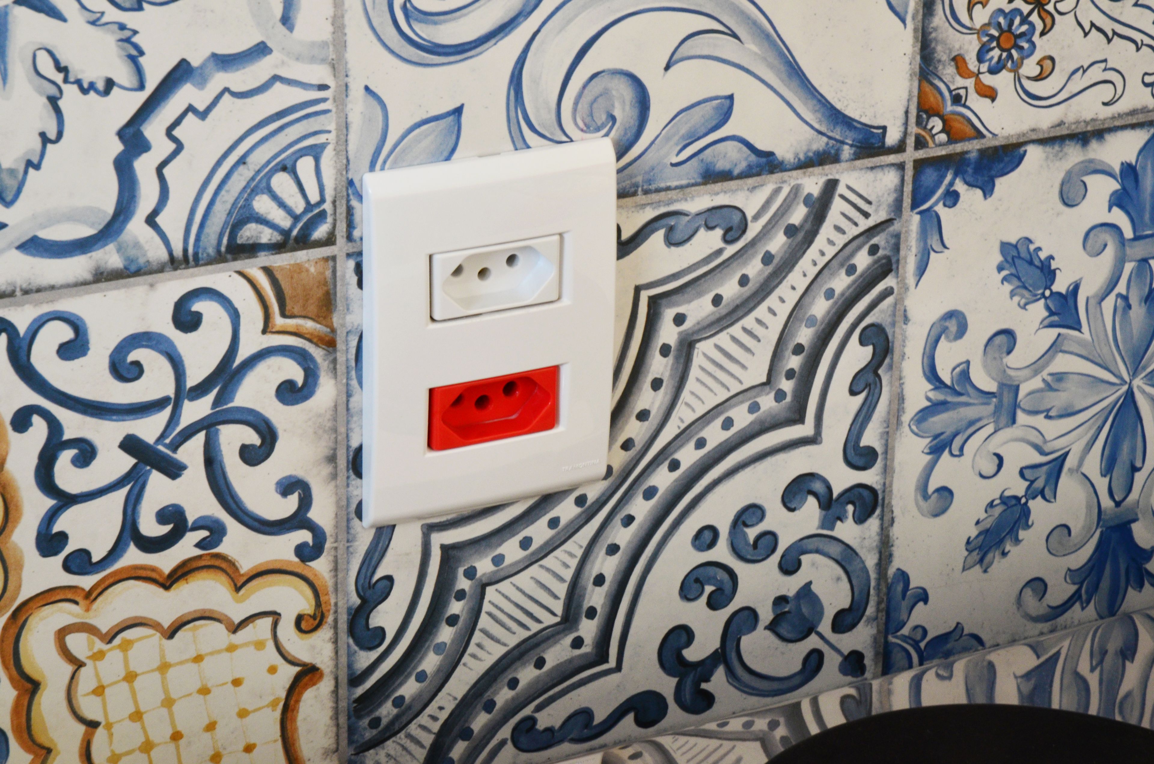 A tiled wall with a power outlet.