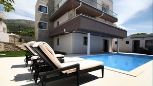 Una casa moderna de dos plantas con piscina, mobiliario exterior y fachada de piedra.