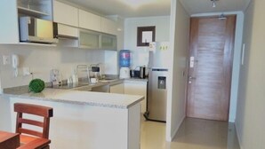 A compact kitchen with white cabinets, a built-in microwave, a coffee maker, and a refrigerator. - Depto Jardín del Mar La serena 941 (Coquimbo)