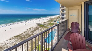Een balkon met uitzicht op een strand en zwembad.