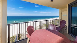 Un balcon avec vue sur la plage, une table et deux chaises.