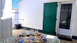 A table with a floral tablecloth and wine glasses, a green door, and a white wall. - 2 Room Mais., Pool, BBQ, Near the Sea (Bretignolles-sur-Mer)