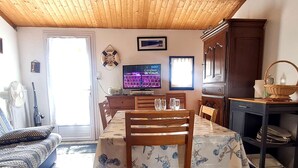 A dining area with a table set for four, wooden chairs, a television, and a wooden ceiling. - 2 Room Mais., Pool, BBQ, Near the Sea (Bretignolles-sur-Mer)