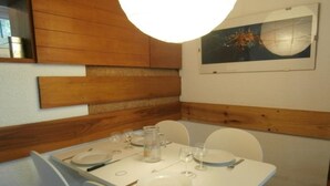 A dining area with a table set for four, white chairs, and a painting on the wall.