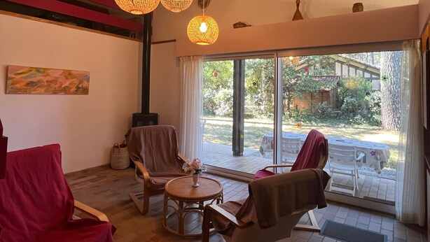 A cozy room with a fireplace, wicker furniture, and a large window offering a view of the outdoors.