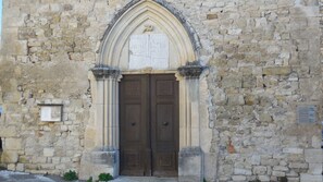 Un bâtiment en pierre doté d’une grande porte en bois, de colonnes et d’une plaque commémorative.