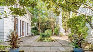 A courtyard with a central water feature, surrounded by potted plants and trees.