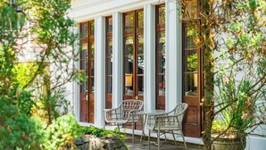A covered patio with wicker chairs and a stone fire feature.