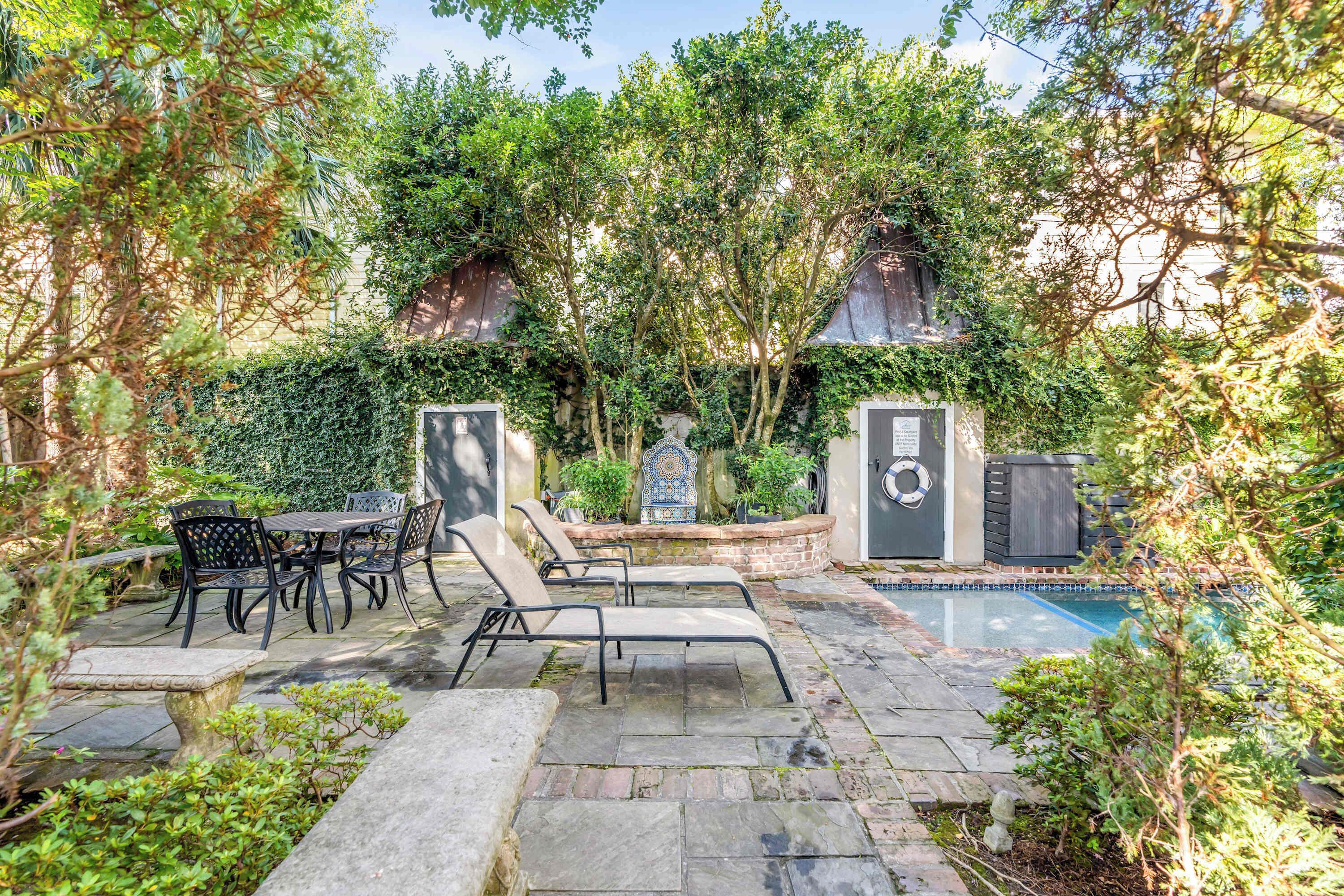 Une terrasse extérieure avec une piscine, un sol en pierre et un espace détente comprenant des chaises et une table.