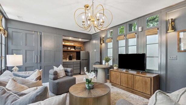 A modern living room with a grey sofa set, a round coffee table with a plant, a TV, and a wooden cabinet.
