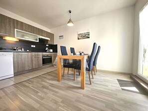 Eine moderne Küche mit Holzausstattung, integriertem Backofen und einer Essecke mit einem Holztisch und Stühlen.
