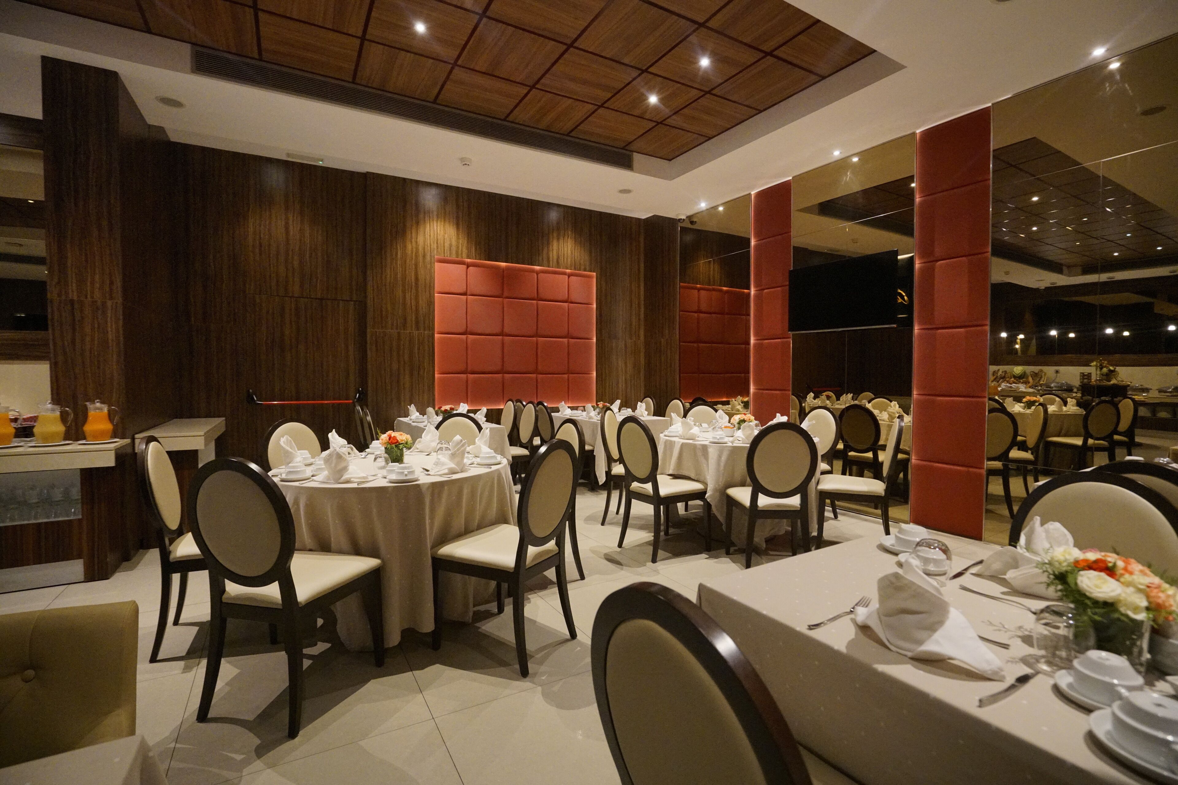 Un comedor con mesas redondas, sillas y un sistema de buffet.