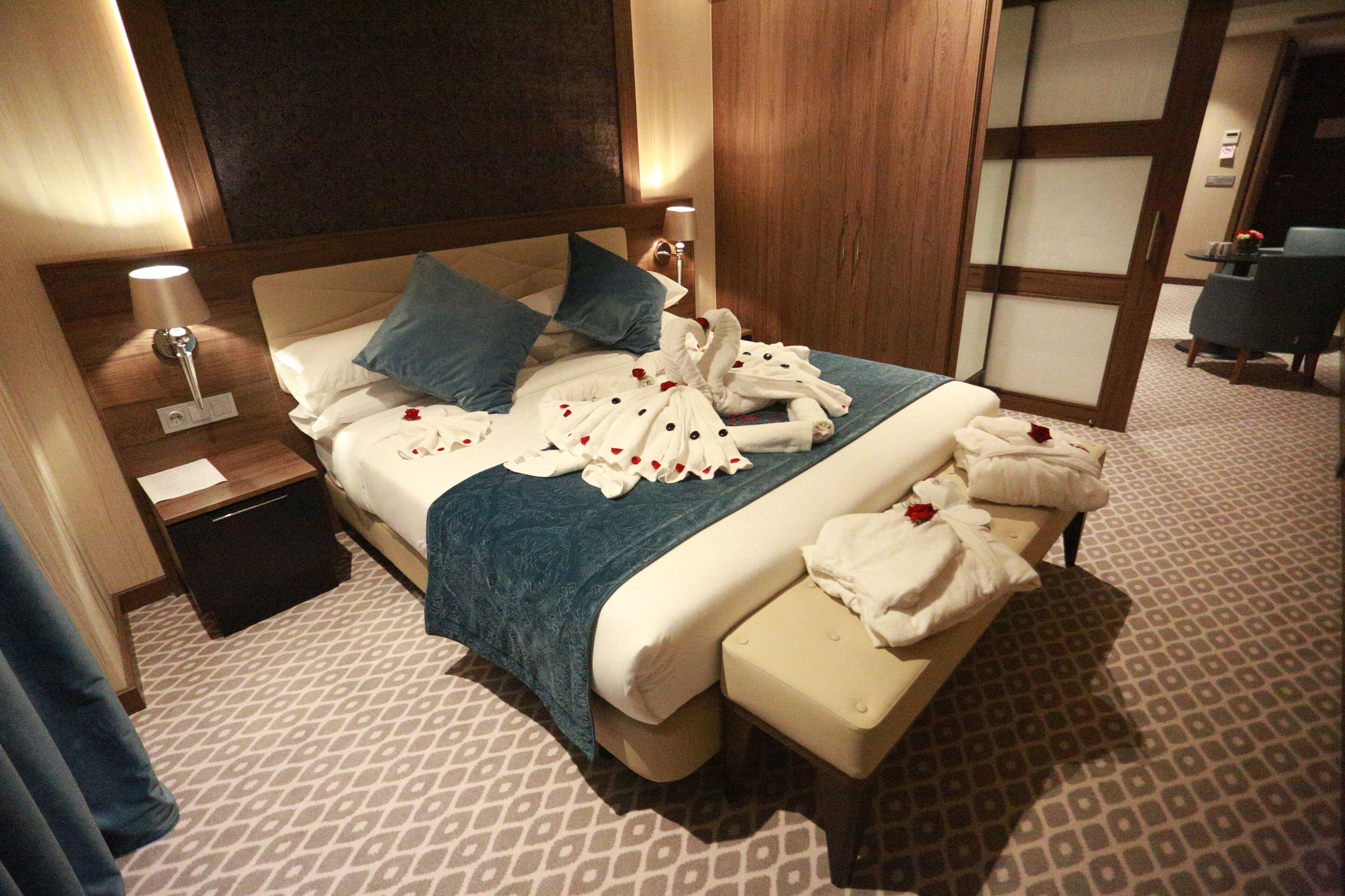 Una habitación de hotel con cama, mesitas de noche, un banco y un área de descanso.