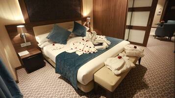 Una habitación de hotel con cama, mesitas de noche, un banco y un área de descanso.