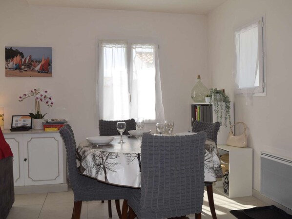 Un coin repas avec une table dressée pour deux personnes, une bibliothèque et une fenêtre avec des rideaux.