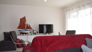 A living room with a television, a sailboat model, a chair, and a sofa.