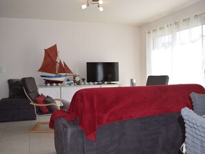 Ein Wohnzimmer mit Fernseher, einem Modell eines Segelbootes, einem Sessel und einer Couch.