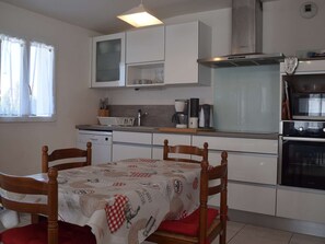 A compact kitchen with white cabinets, a built-in oven, and a dining table with chairs.
