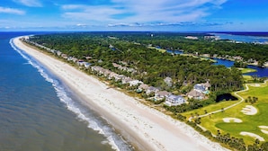 Luchtbeeld van een kustgebied met woonwijken, huizen aan het strand, een golfbaan en een meer.