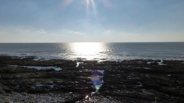 Une côte rocheuse, avec le soleil qui brille sur l’eau.