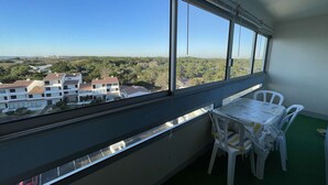 A balcony with a table and chairs, overlooking a residential area with buildings and greenery.