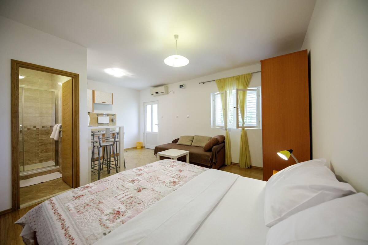 Quarto de hotel com cama, escrivaninha, sofá e área de duche.